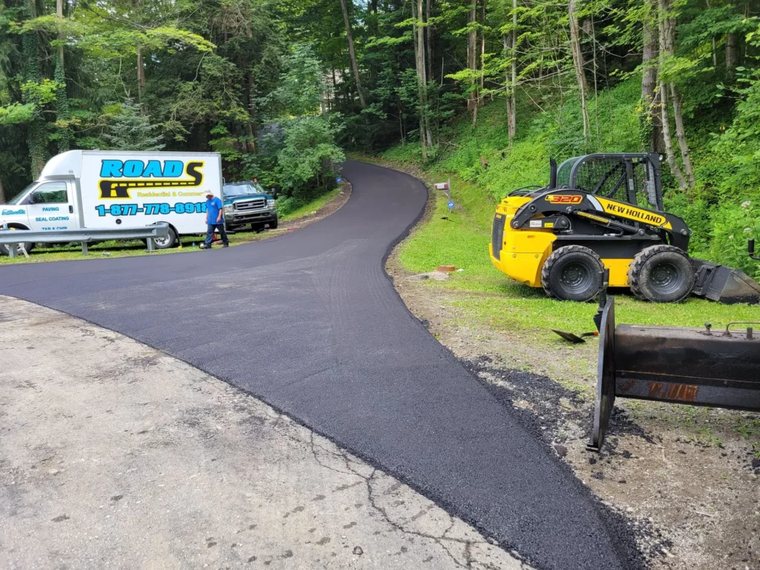 Roads Paving crew paving a long wooded driveway in Erie County
